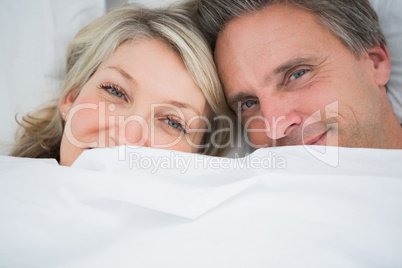 Couple smiling from under the covers