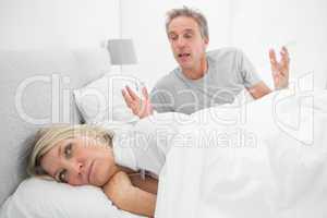 Man arguing with his partner in bed