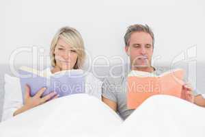 Relaxed couple reading in bed