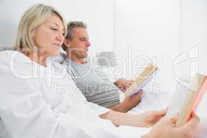 Relaxed couple reading books in bed