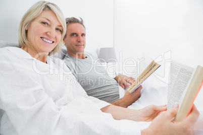 Happy couple reading books in bed
