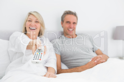 Laughing couple watching tv in bed