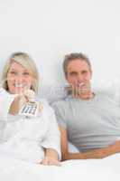 Relaxed couple watching tv in bed