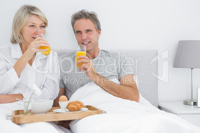 Couple drinking orange juice having breakfast in bed