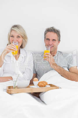 Couple having orange juice at breakfast in bed