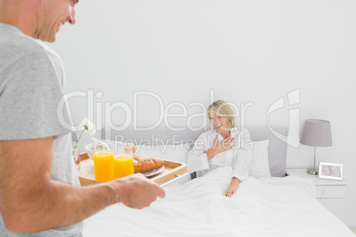 Man bringing breakfast in bed to his partner