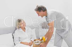 Caring man bringing breakfast in bed to his partner