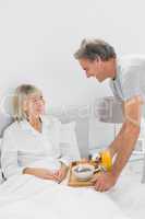 Considerate man bringing breakfast in bed to his partner