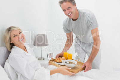 Considerate man giving breakfast in bed to his partner