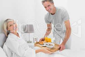 Considerate man giving breakfast in bed to his partner