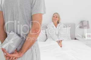 Man hiding present behind his back for partner