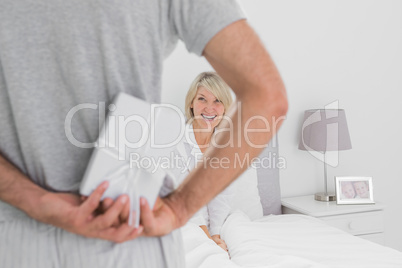 Man hiding present behind his back for smiling partner