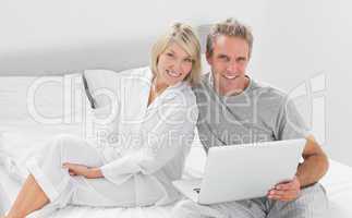 Couple with laptop smiling at camera