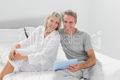 Couple using their digital tablet smiling at camera