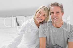 Cheerful couple sitting on bed
