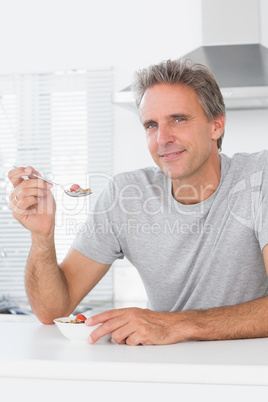 Happy man having cereal for breakfast in kitchen