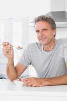 Happy man having cereal for breakfast in kitchen