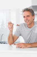 Cheerful man having cereal for breakfast in kitchen
