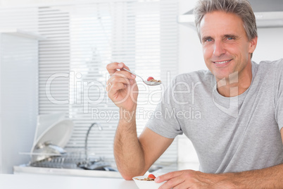 Happy man having cereal for breakfast in kitchen