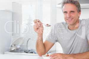 Happy man having cereal for breakfast in kitchen