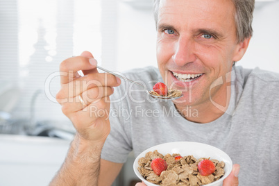 Cheerful man eating cereal for breakfast