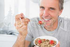 Cheerful man eating cereal for breakfast
