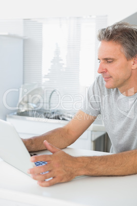 Happy man using laptop in kitchen