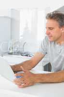 Happy man using laptop in kitchen