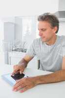 Smiling man using tablet pc in kitchen