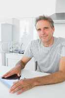 Cheerful man using tablet pc in kitchen