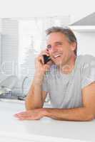 Laughing man making phone call in kitchen