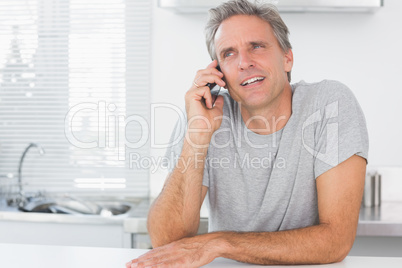 Happy man making phone call in kitchen