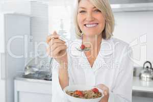 Smiling blonde eating cereal for breakfast