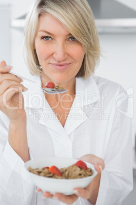 Happy blonde eating cereal for breakfast