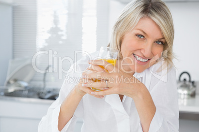 Smiling blonde having orange juice in kitchen