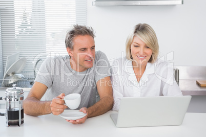 Happy couple using laptop in the morning