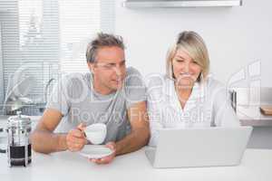 Happy couple using laptop in the morning