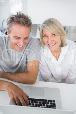 Smiling couple using their laptop in the morning