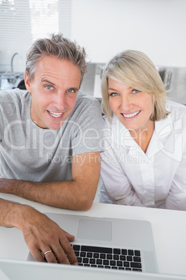 Smiling couple using their laptop in the morning looking at came