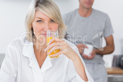 Woman drinking orange juice in kitchen