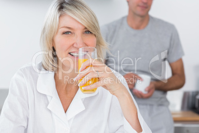 Blonde drinking orange juice in kitchen