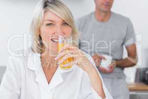 Blonde drinking orange juice in kitchen