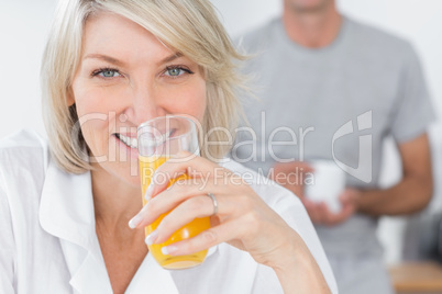 Happy woman drinking orange juice in kitchen