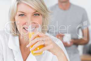 Happy woman drinking orange juice in kitchen