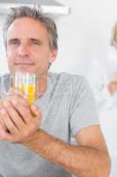 Cheerful man drinking orange juice in kitchen