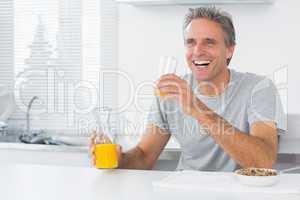 Happy man having orange juice with breakfast