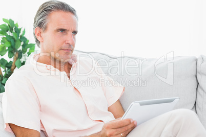 Man relaxing on his couch using tablet pc