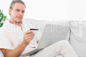Man on his couch using laptop for online shopping