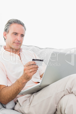 Man on his couch using laptop for shopping online