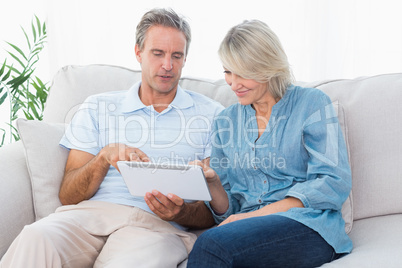 Couple using tablet together on the sofa